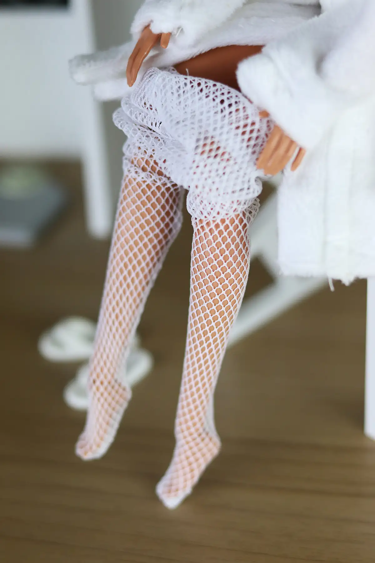 Close-up of Barbie Looks Lina doll putting on white fishnet stockings